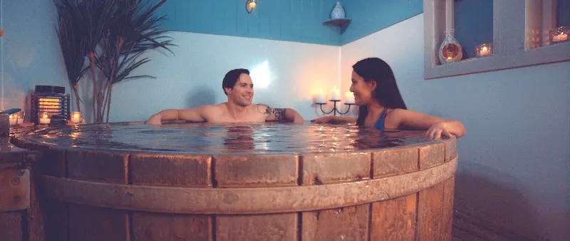 Couple relaxing in a wooden mineral hot tub by candlelight at Te Aroha Mineral Spas.