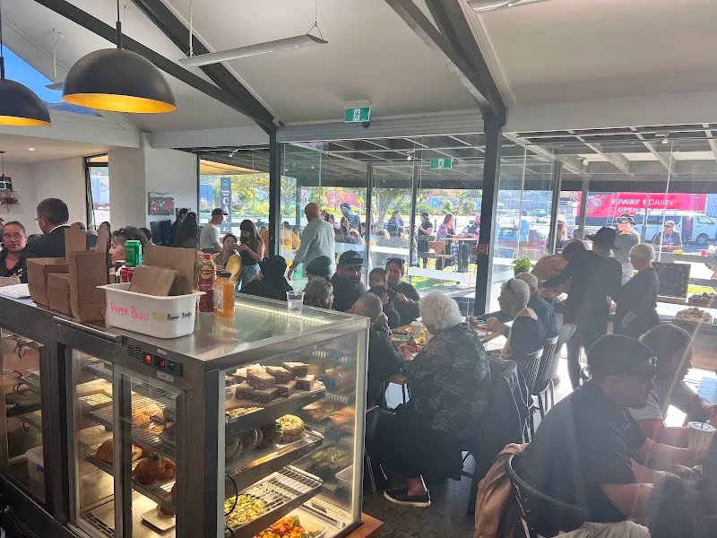 Bustling indoor seating and fresh bakery cabinet at Breaking Bread Cafe in Pōkeno.