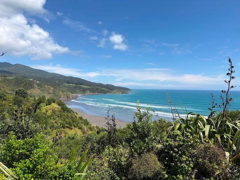 Rolling surf point break waves along the rugged Raglan coastline at Whale Bay beneath Mt Karioi.