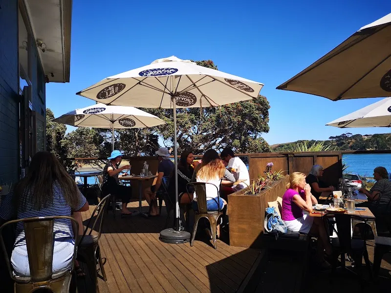 Sunny waterfront dining deck at Orca Eatery & Bar overlooking Raglan Harbour.