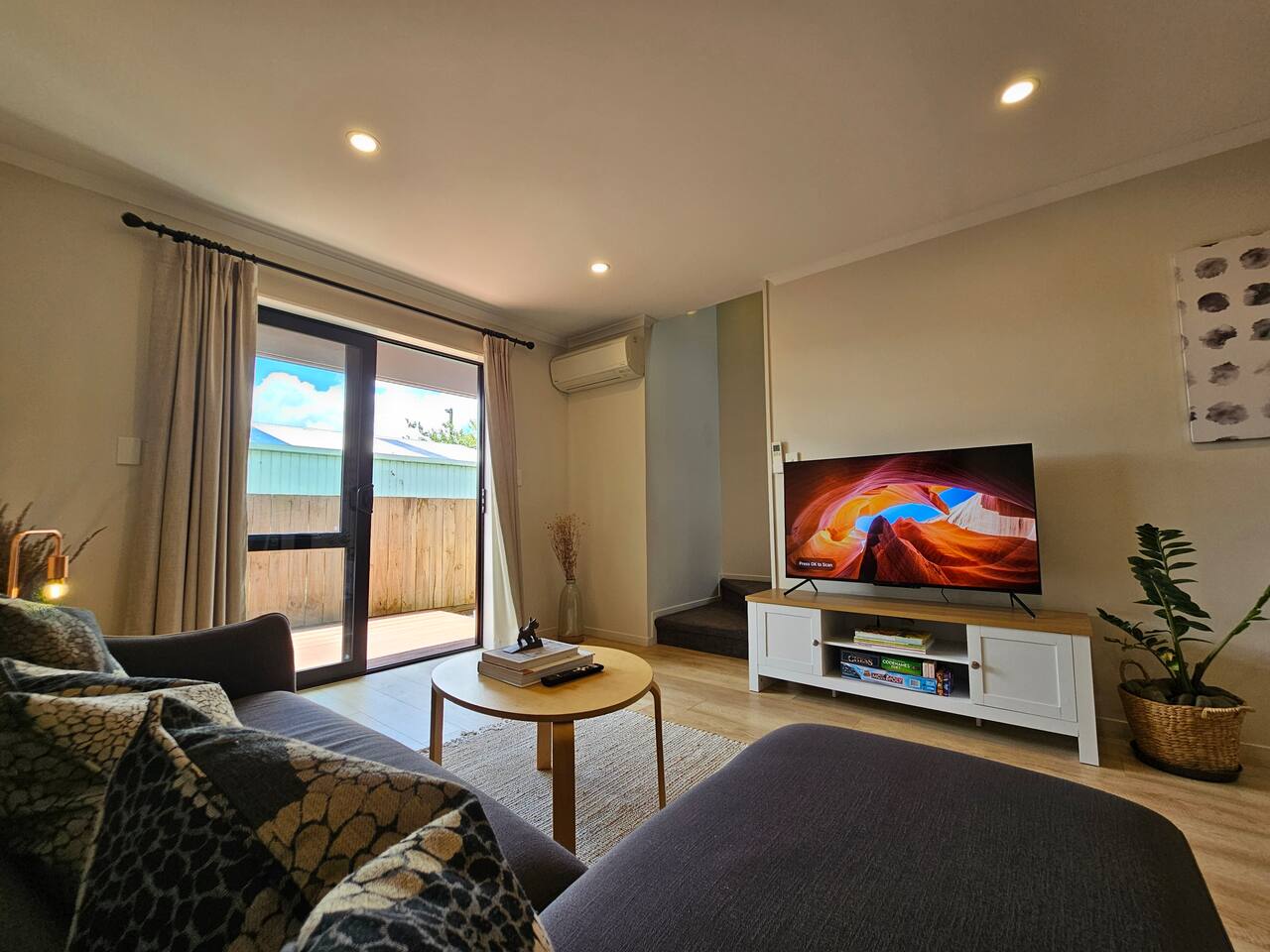 Sofa and round coffee table facing a television beside sliding patio doors.