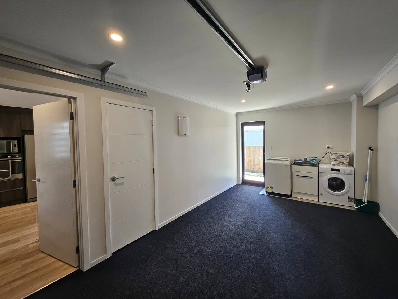 Internal garage with laundry appliances and a doorway into the kitchen.